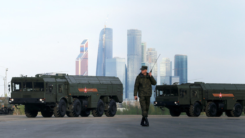 Seorang tentara Rusia berjalan di depan peluncur misil Iskander-M di Moskow.