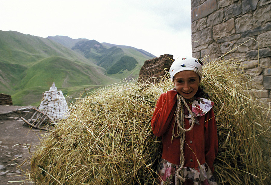 Девушка, несущая сено во время сбора урожая в Дагестане, Агульский район, Россия.