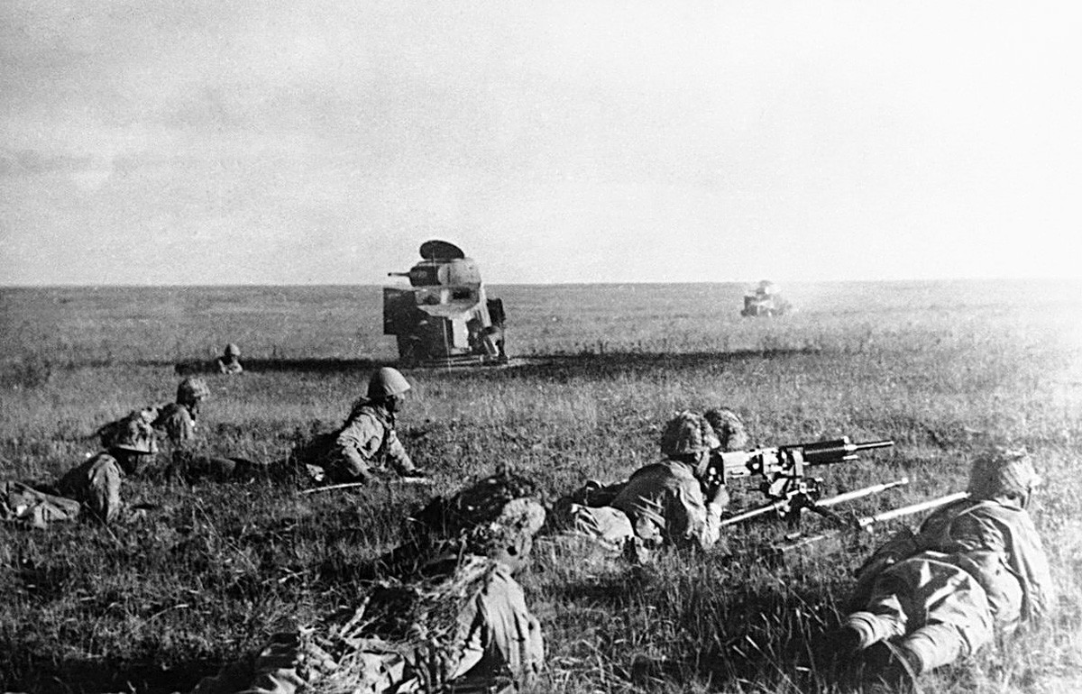 Japanski vojnici pucaju iz ležećeg položaja ispred uništenih sovjetskih tenkova.

