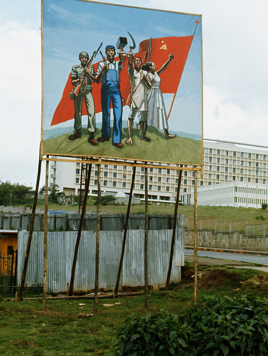 Cartel de propaganda muestra a unos etíopes sosteniendo símbolos comunistas junto a la bandera soviética, en Addis Abeba (Etiopía), 1977 