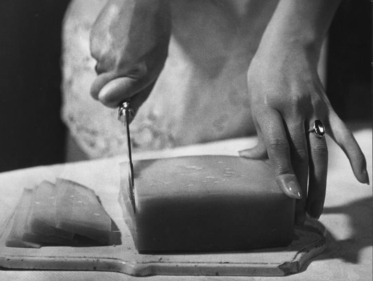 Es difícil determinar exactamente qué hay debajo del cuchillo: ¿mantequilla, queso o tocino? El misterio inherente vuelve a la foto algo inquietante (1957). 
