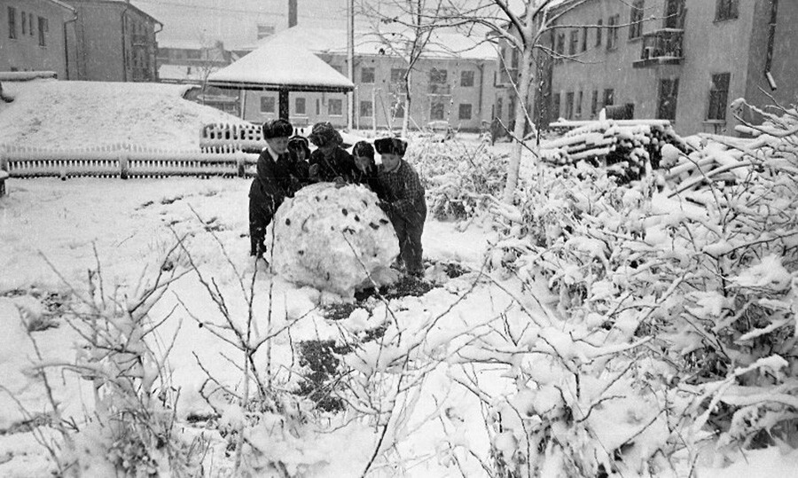 1960年代、力を合わせて雪だるまを作る子どもたち。