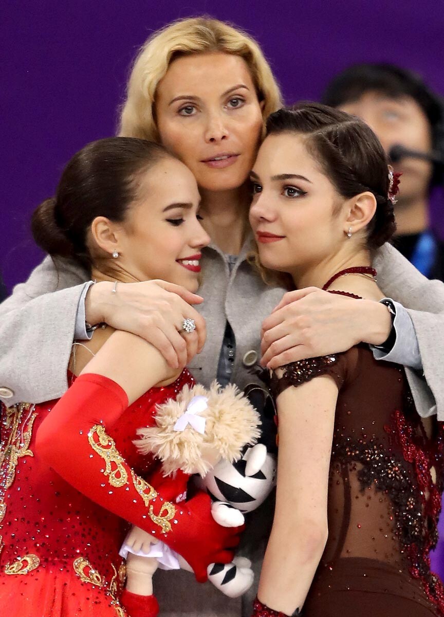 Pemenang medali emas Alina Zagitova (kiri) dan pemenang medali perak Evgenia Medvedeva (kanan) merayakan kemenangan bersama pelatih mereka, Eteri Tutberidze (tengah), pada Olimpiade Musim Dingin PyeongChang 2018 di Gelanggang Es Gangneung, 23 Februari 2018 di Gangneung, Korea Selatan.