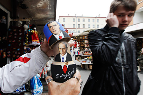 Seorang penjual menunjukkan cara membuka boneka Matryoshka dengan wajah Perdana Menteri Rusia Vladimir Putin dan Presiden Rusia Dmitry Medvedev kepada turis yang lewat di pasar suvenir di Sankt Peterburg, 26 September 2011.