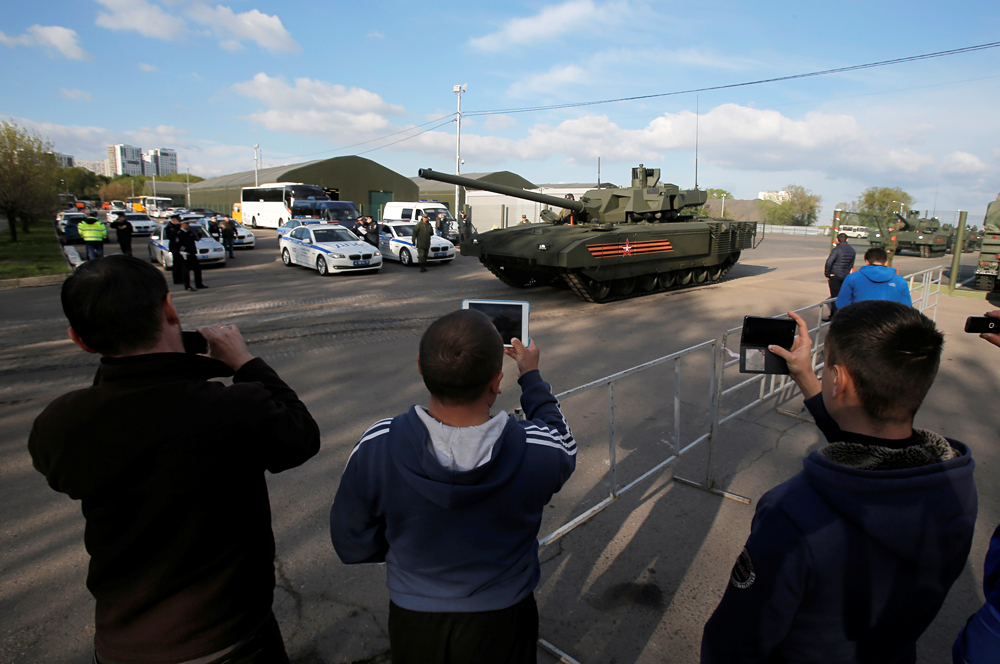 Orang-orang mengambil foto tank T-14 dengan platform tempur universal Armata saat kendaraan lapis baja ini meninggalkan medan militer untuk ikut dalam latihan parade Hari Kemenangan di Moskow, Rusia, 5 Mei 2016.