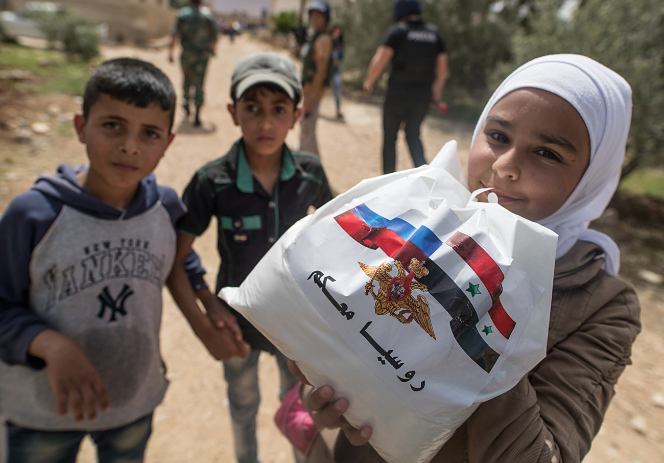 Anak-anak menerima bantuan kemanusiaan Rusia di permukiman Alkin, Kegubernuran Daraa, Suriah.