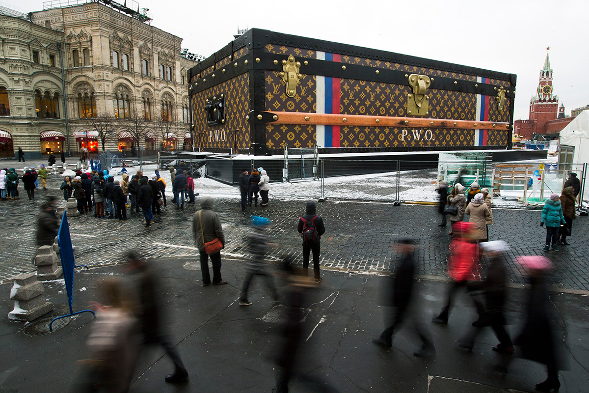 Turistas y visitantes pasan por una maleta gigantesca de Louis Vuitton colocada en la Plaza Roja el 27 de noviembre de 2013. El baúl, de 30 metros de largo y 10 metros de alto, no tardó en retirarse de la Plaza Roja por la respuesta negativa del público.
