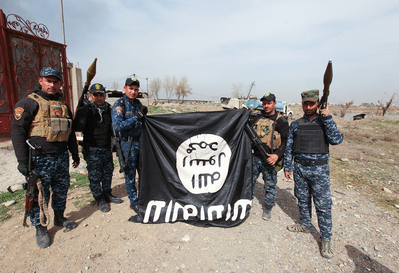 Anggota tentara Irak memegang bendera ISIS yang mereka ambil dalam sebuah pertempuran dengan para teroris itu pada 12 Februari 2017.